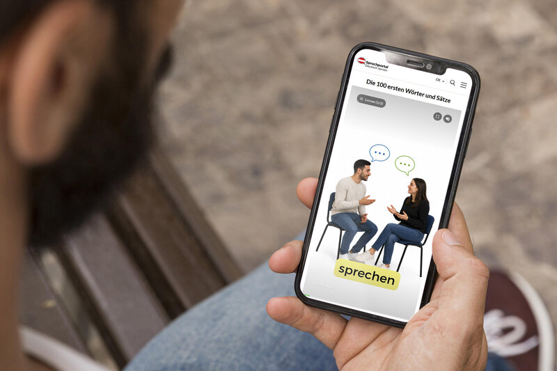 Smartphone zeigt Sprachportal-App mit Gespräch zweier Personen