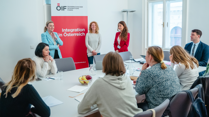 Besprechung zum Thema Integration in Österreich mit mehreren Teilnehmenden und Präsentation im Hintergrund.