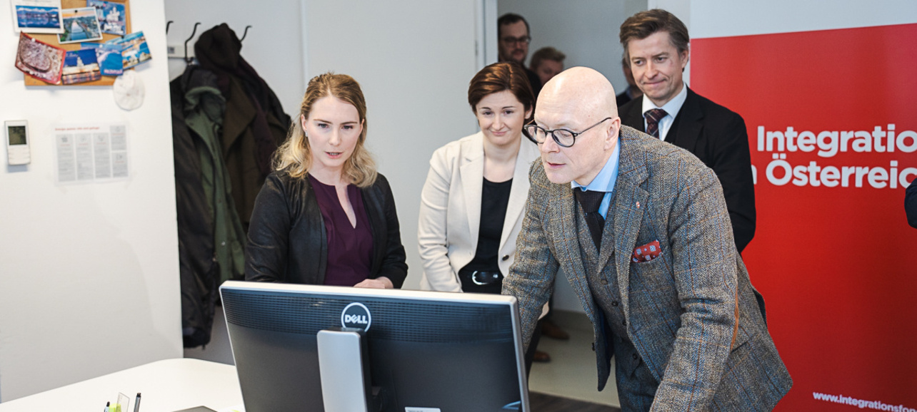 Menschen betrachten einen Computerbildschirm in einem Büro.