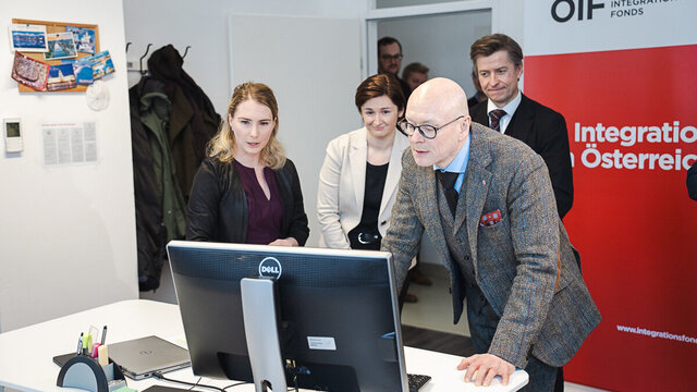 Menschen betrachten einen Computerbildschirm in einem Büro.