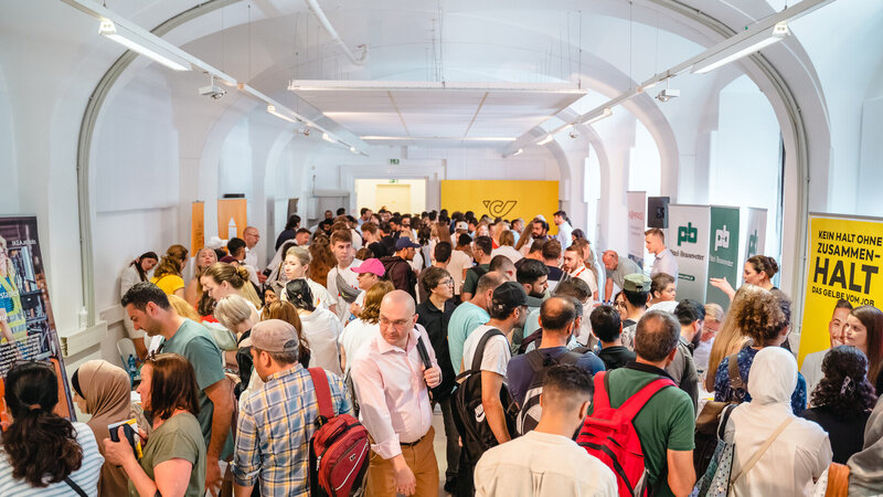 Ein großer Menschenauflauf in einem Innenraum, der ein Lebendigkeits- und Vernetzungs-Event zeigt.