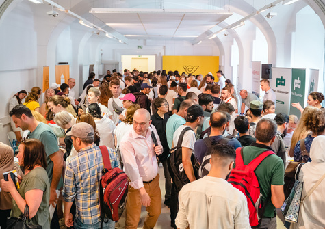 Ein großer Menschenauflauf in einem Innenraum, der ein Lebendigkeits- und Vernetzungs-Event zeigt.
