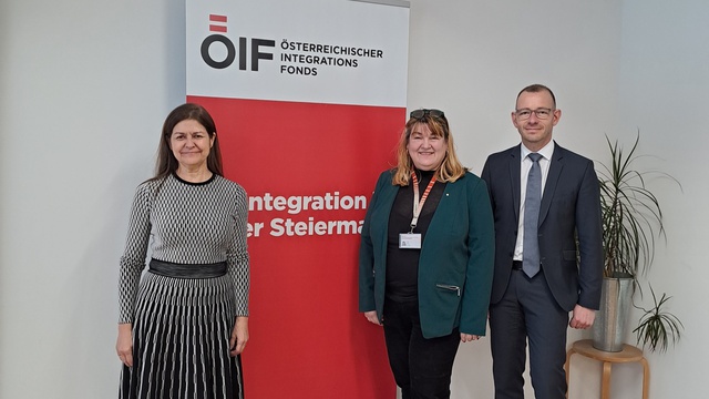 Drei Personen stehen vor einem Banner des Österreichischen Integrationsfonds in einem hellen Raum.