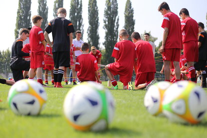 Jugendliche Fußballmannschaft im roten Trikot trainiert auf Rasenplatz