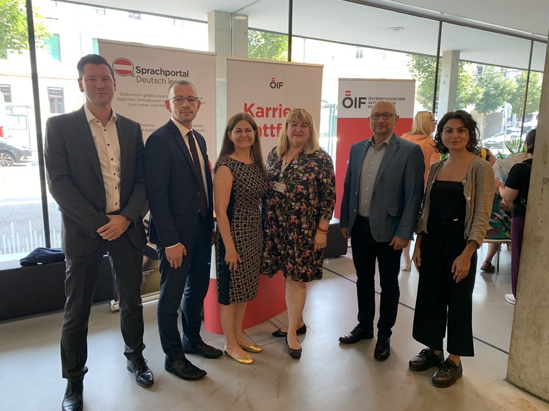 Sechs Personen stehen lächelnd vor Hintergrundbanner zu Sprachportal und Karriere.