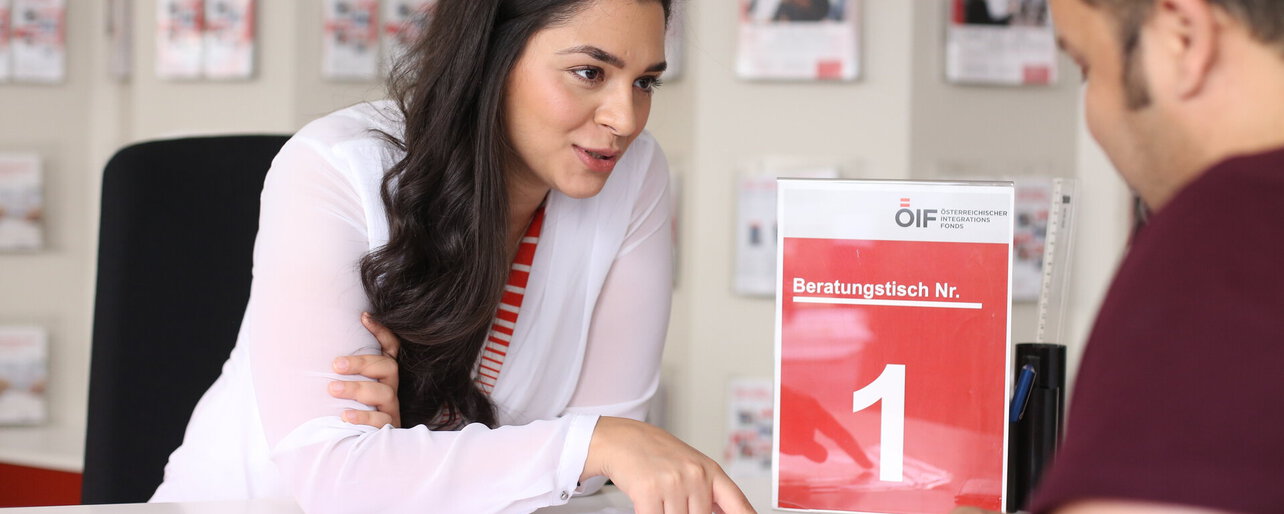 Beraterin am Beratungstisch mit Beratungsmaterialien des Österreichischen Integrationsfonds