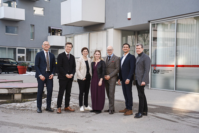 Gruppe von sieben Menschen vor einem Gebäude.