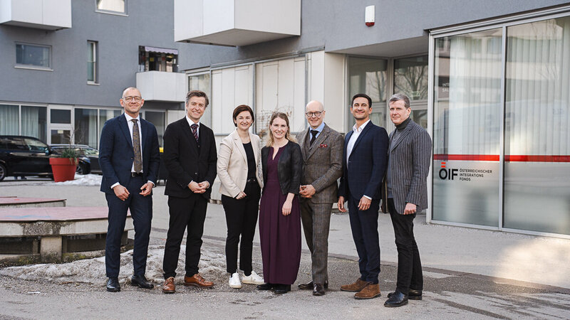 Gruppe von sieben Menschen vor einem Gebäude.