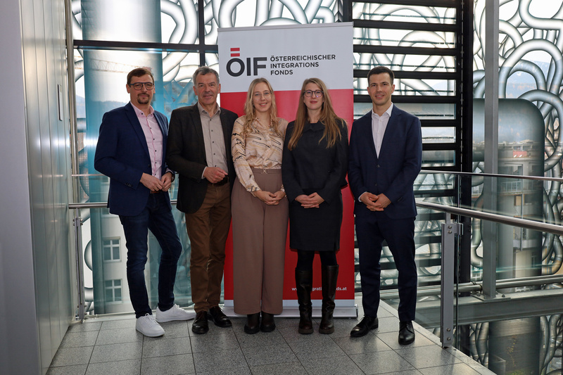 Fünf Personen stehen vor einem Banner des Österreichischen Integrationsfonds.