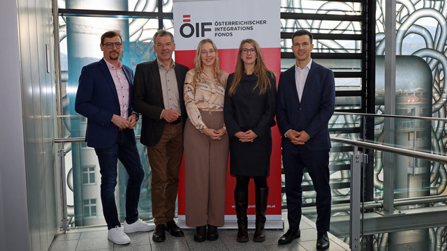 Fünf Personen stehen vor einem Banner des Österreichischen Integrationsfonds.