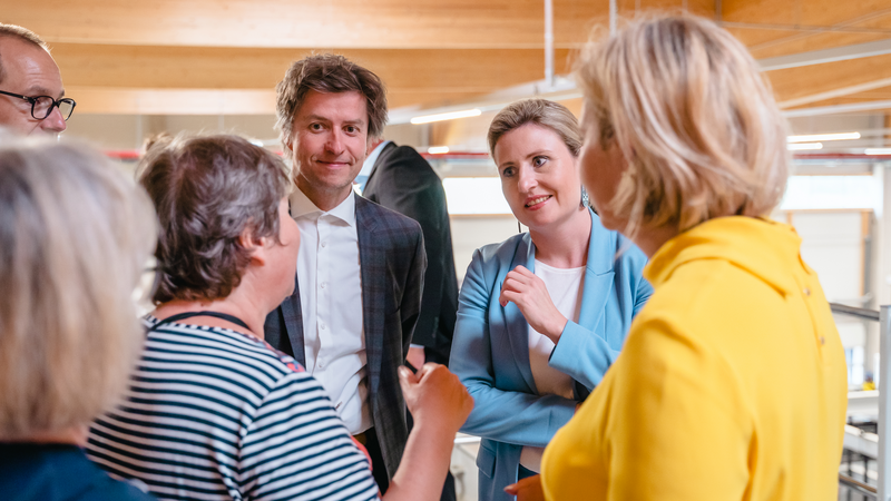 Eine Gruppe von Menschen diskutiert aufmerksam in einem modernen Innenraum.