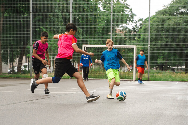 Kinder spielen Fußball auf Sportplatz