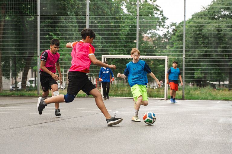 Kinder spielen Fußball auf Sportplatz