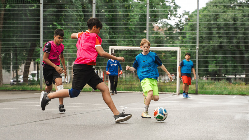 Kinder spielen Fußball auf Sportplatz