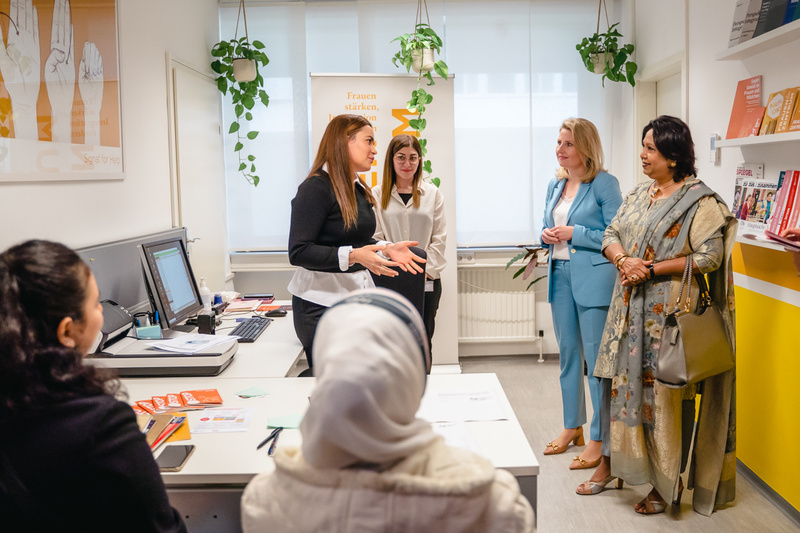 Fünf Frauen in einem Büro diskutieren über Empowerment und Unterstützung für Frauen.