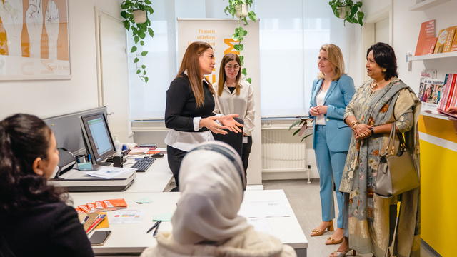 Fünf Frauen in einem Büro diskutieren über Empowerment und Unterstützung für Frauen.