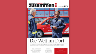 Zwei Männer in Feuerwehruniform unterhalten sich vor einem roten Feuerwehrfahrzeug.