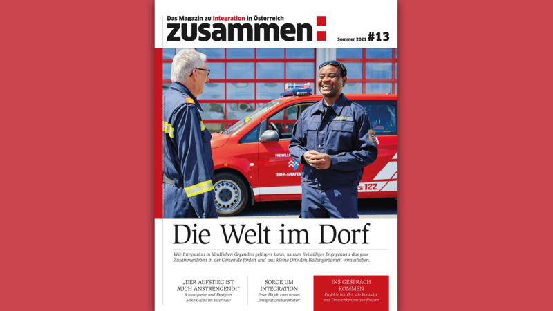Zwei Männer in Feuerwehruniform unterhalten sich vor einem roten Feuerwehrfahrzeug.