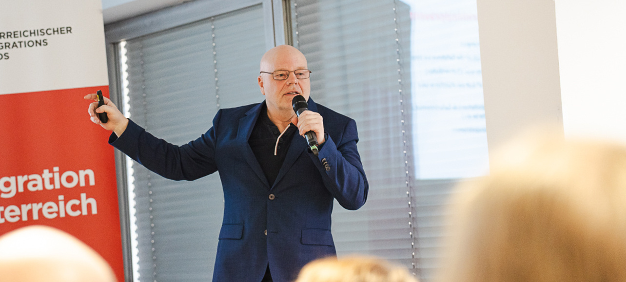 Mann spricht auf einer Veranstaltung zur Migration.