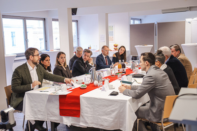 Eine Gruppe von Personen sitzt an einem Tisch und führt eine Diskussion während eines Meetings.