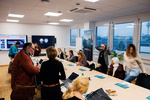 Eine Gruppe von Menschen beim Gespräch in einem modernen Konferenzraum mit mehreren Laptops und Präsentationsbildschirmen.