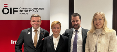 Vier Personen stehen zusammen vor einem Banner des Österreichischen Integrationsfonds.