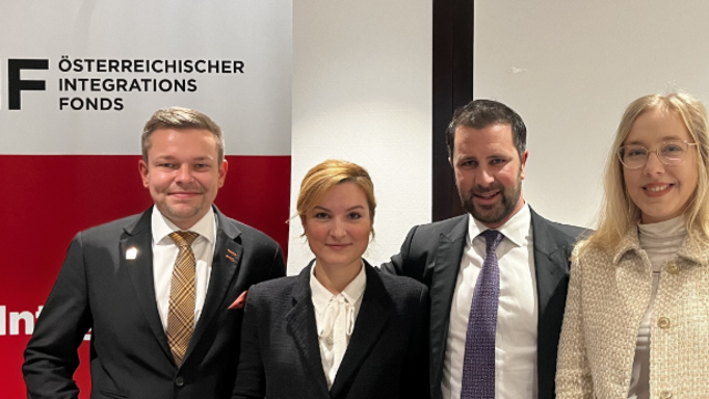 Vier Personen stehen zusammen vor einem Banner des Österreichischen Integrationsfonds.
