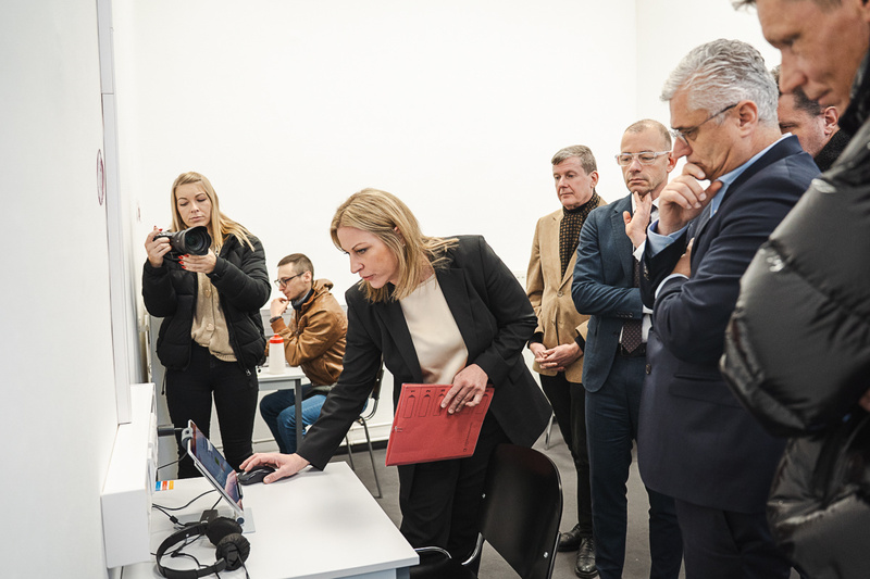 Eine Frau bedient ein Tablet, während eine Gruppe von Menschen beobachtet.
