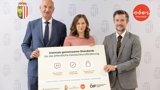 Integrationslandesrat Dr. Christian Dörfel, Bundesministerin Claudia Bauer und ÖIF-Direktor Franz Wolf präsentieren gemeinsam eine Informationstafel zu einheitlichen Standards für die öffentliche Deutschkursförderung.