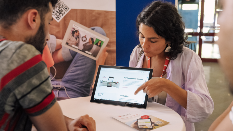 Eine Person präsentiert eine Website auf einem Tablet bei einem Beratungsgespräch.