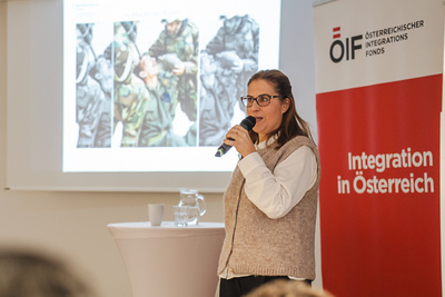 Frau spricht mit Mikrofon bei einer Präsentation.