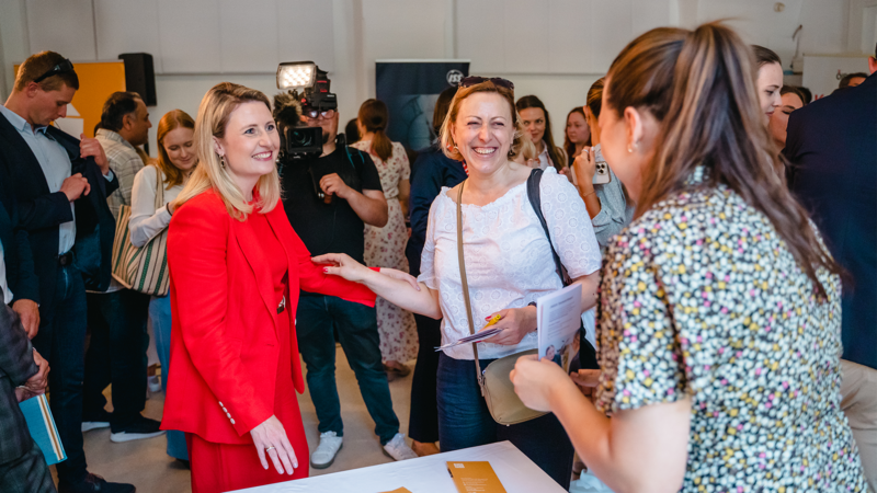Zwei Frauen unterhalten sich fröhlich auf einem Event, während eine weitere Person in der Nähe steht.