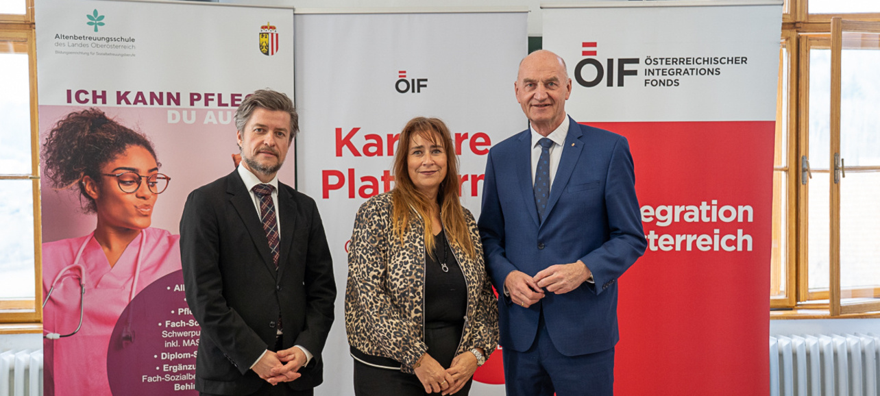 Drei Personen stehen vor Informationsbanner zur Karriere.