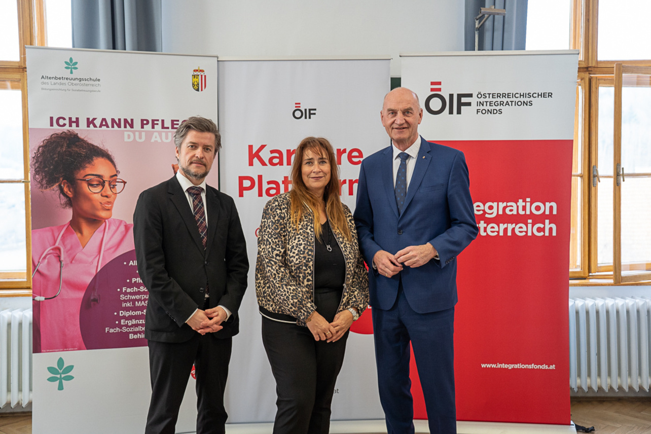 Drei Personen stehen vor Informationsbanner zur Karriere.