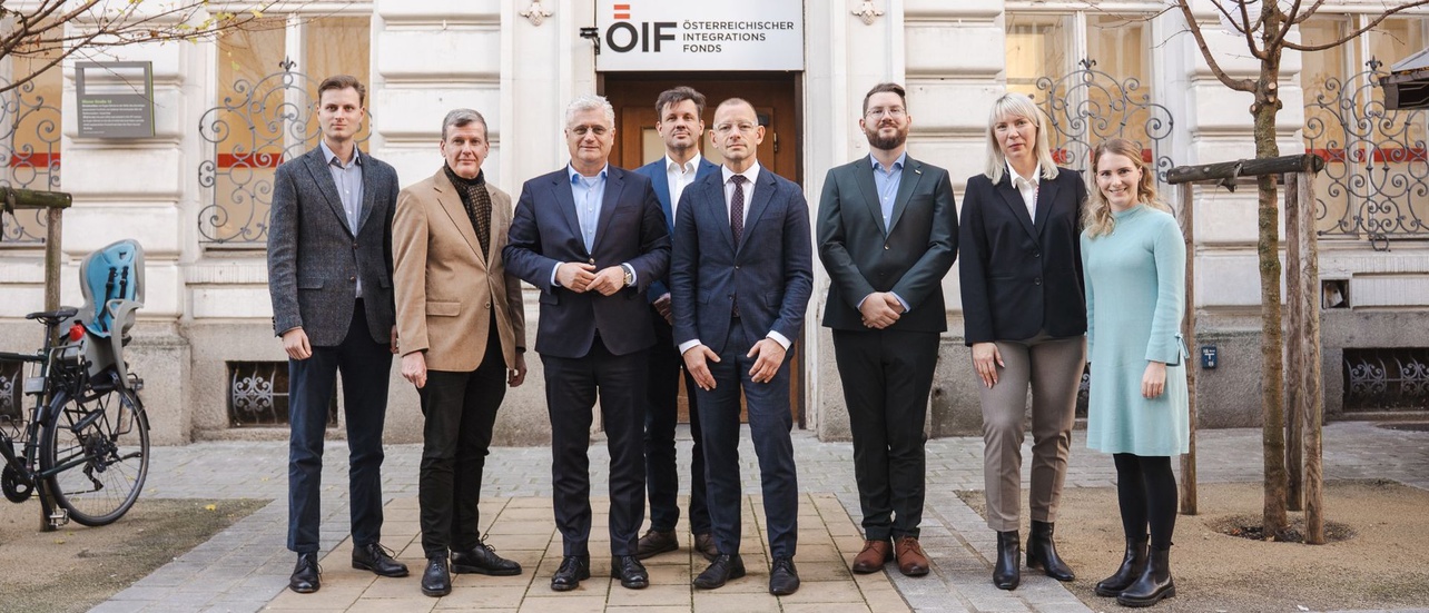 Gruppe von neun Personen steht vor einem Gebäude mit dem Schriftzug „Österreichischer Integrationsfonds“.