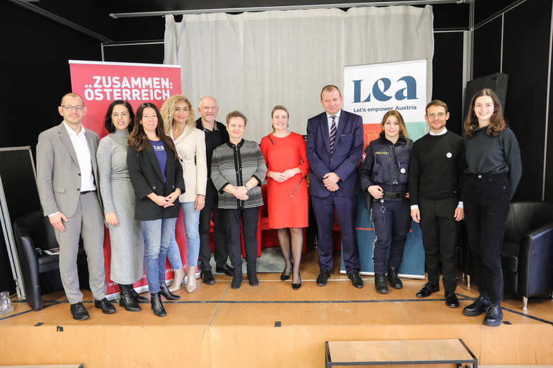 Gruppe von Personen steht vor einer Bühne mit Bannern für "Zusammen: Österreich" und "LEA".