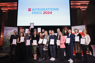Gruppenfoto von Preisträgern des Integrationspreises 2024, alle halten Zertifikate in der Hand.