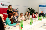 Eine Gruppe von Menschen diskutiert an einem Tisch, umgeben von Wasserflaschen und Informationsmaterialien.