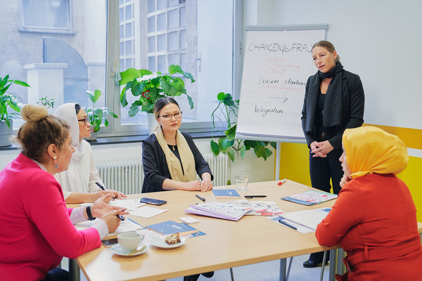 Ein Workshop mit fünf Frauen, die über Chancen und Integration diskutieren, während ein Flipchart im Hintergrund steht.