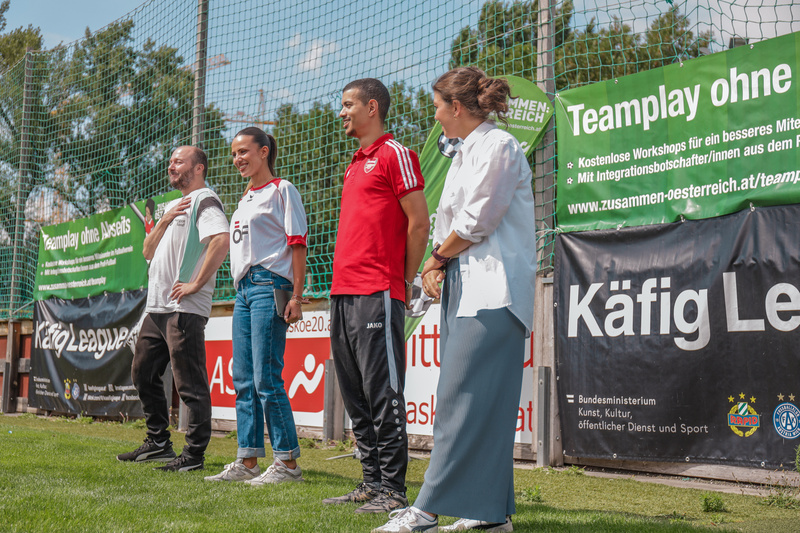 Vier Personen stehen an einem Fußballfeld, während sie an einer Veranstaltung zur Förderung von Teamarbeit teilnehmen.