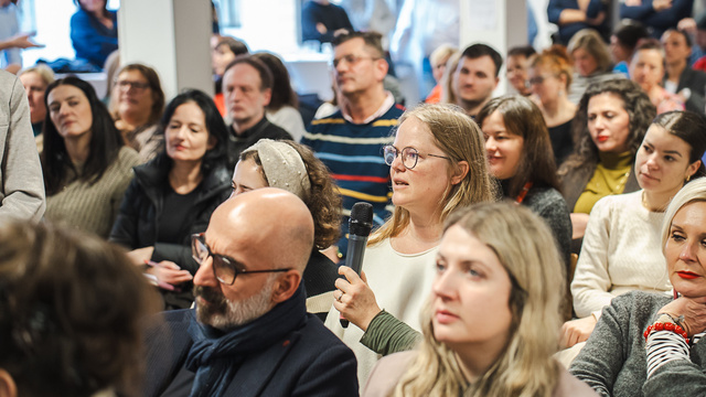 Erwachsene in einer Diskussion mit Fragen und Zuhörern.