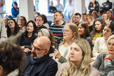 Erwachsene in einer Diskussion mit Fragen und Zuhörern.