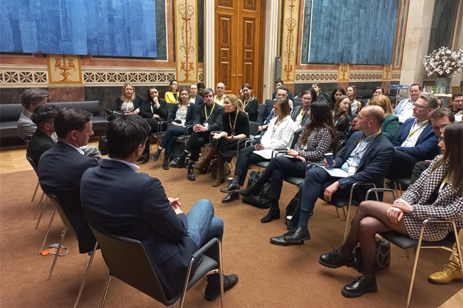 Eine Gruppe von Menschen sitzt in einem Raum und diskutiert. Einige Personen sprechen, während andere zuhören.