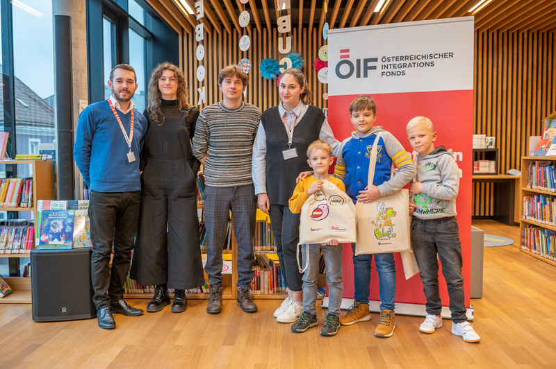 Sechs Personen stehen in einer Bibliothek vor einem Banner des Österreichischen Integrationsfonds.