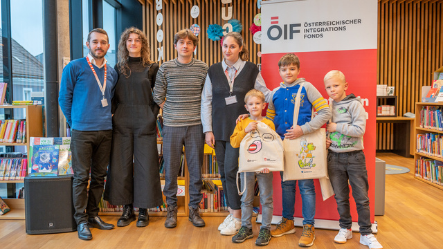 Sechs Personen stehen in einer Bibliothek vor einem Banner des Österreichischen Integrationsfonds.