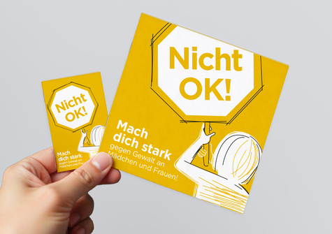 Eine Hand hält ein gelbes Plakat mit der Aufschrift "Nicht OK! Mach dich stark gegen Gewalt an Mädchen und Frauen!"