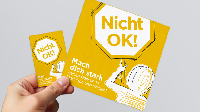 Eine Hand hält ein gelbes Plakat mit der Aufschrift "Nicht OK! Mach dich stark gegen Gewalt an Mädchen und Frauen!"