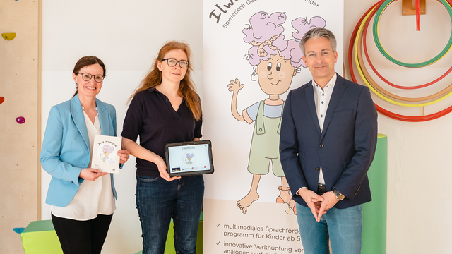 Drei Personen präsentieren das Projekt „Ilwa Immerfrohs“ zur Sprachförderung für Kinder.