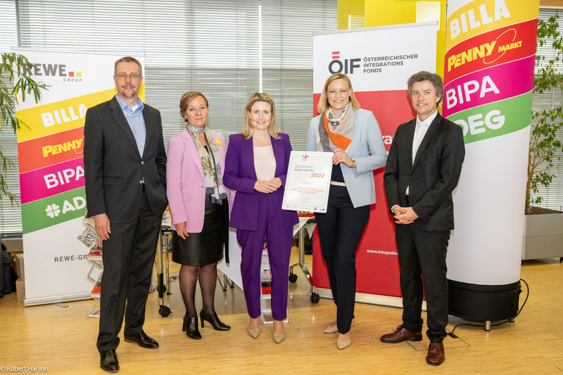 Fünf Personen präsentieren ein Zertifikat für den Österreichischen Integrationsfond in einem modernen Büro.