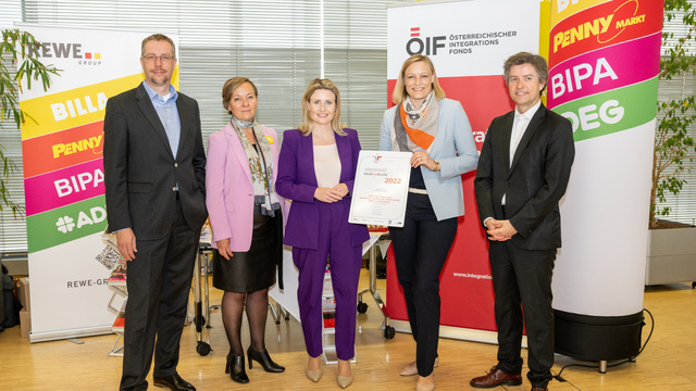 Fünf Personen präsentieren ein Zertifikat für den Österreichischen Integrationsfond in einem modernen Büro.